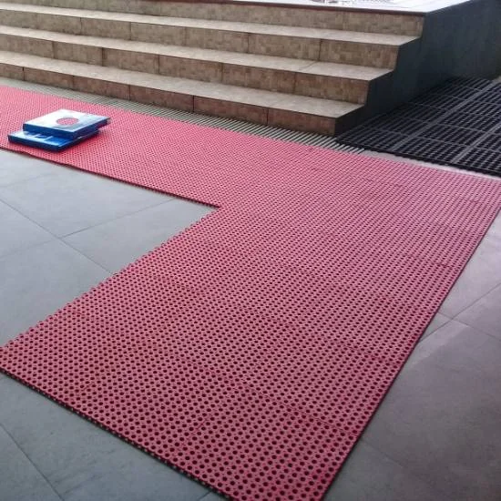 Red anti-slip ablution mat on tiled floor, stairs.