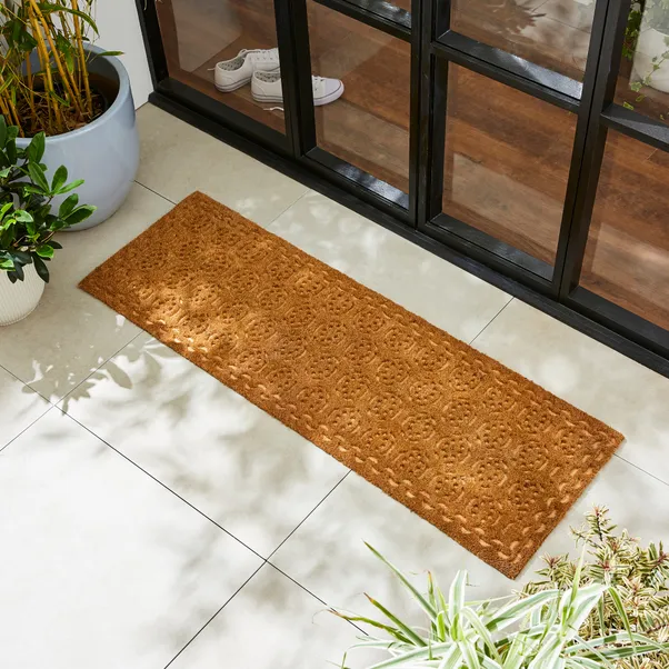 narrow coir runner with a circular pattern on a white tiled floor