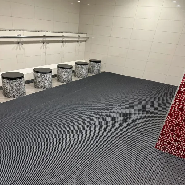 Grey ribbed floor mats, speckled stools, ablution room