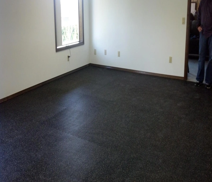 An empty room with speckled black rubber flooring