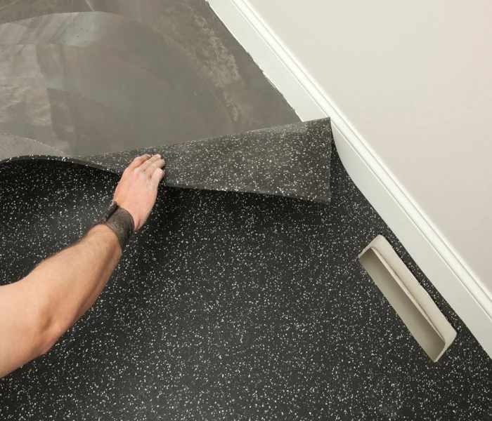 Hand pulling back speckled rubber floor matting