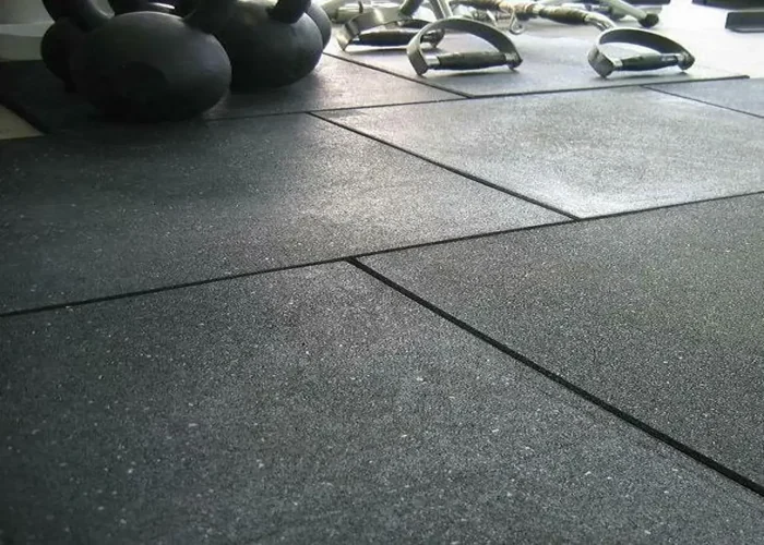 close-up of black rubber gym floor tiles and weights